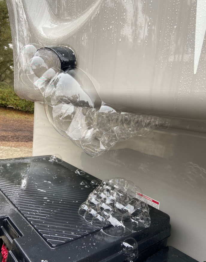 RV plumbing technician inspecting water lines under an RV in Stuart
